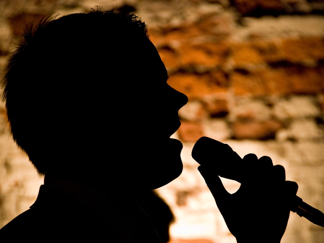 Silhouette of a person singing into a microphone
