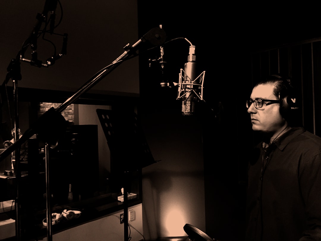 man standing in front of condenser microphone inside recording studio