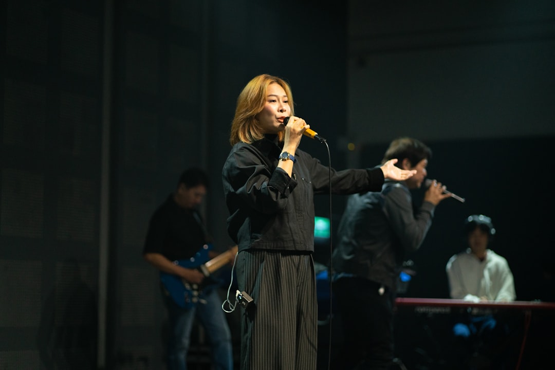 A woman sings into a microphone on stage.