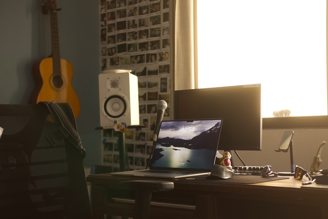Desk with laptop, monitor, and guitar