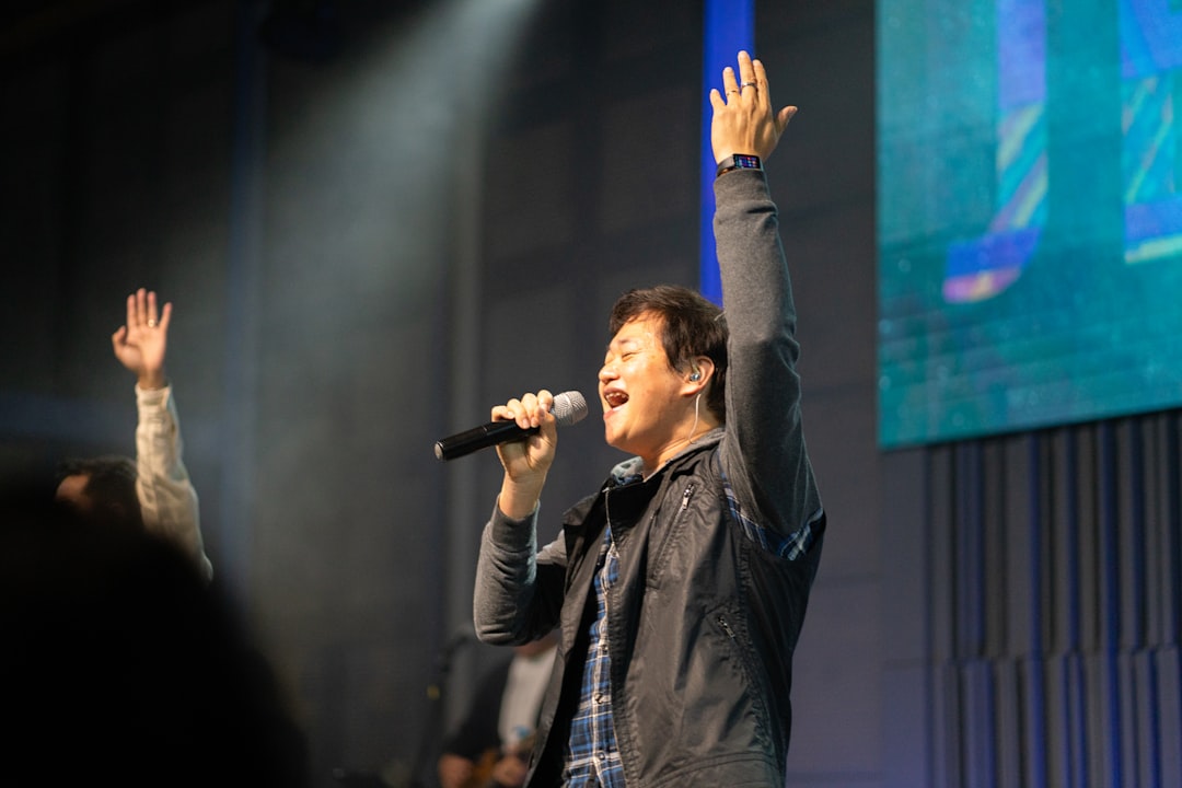 Man singing with hands raised on stage